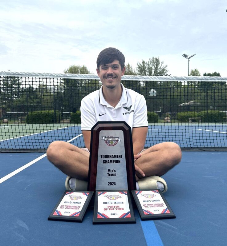 Vasek Schneider on a tennis court with trophies